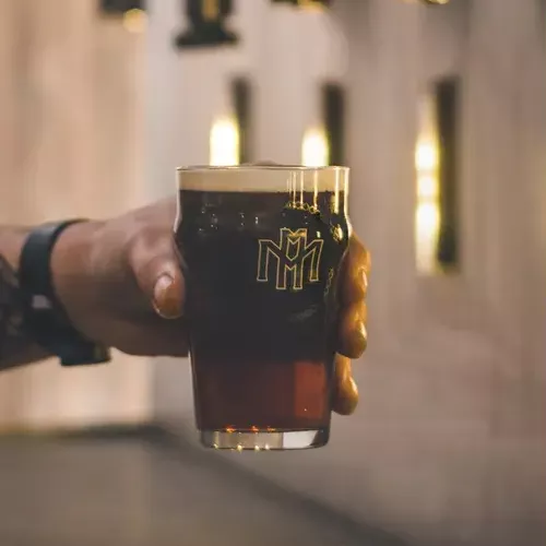 A person's hand holding a beer